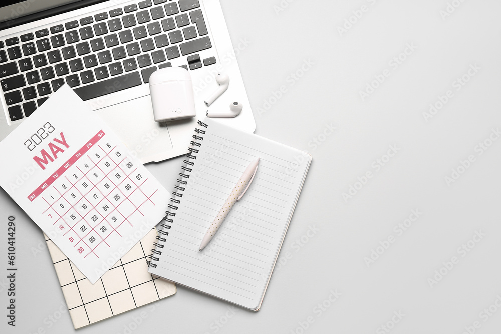 Composition with calendar, modern laptop, notebook and earphones on grey background