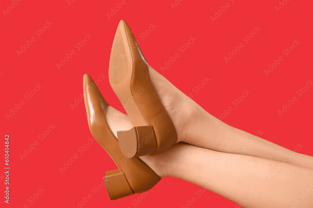 Female legs in stylish shoes on red background, closeup