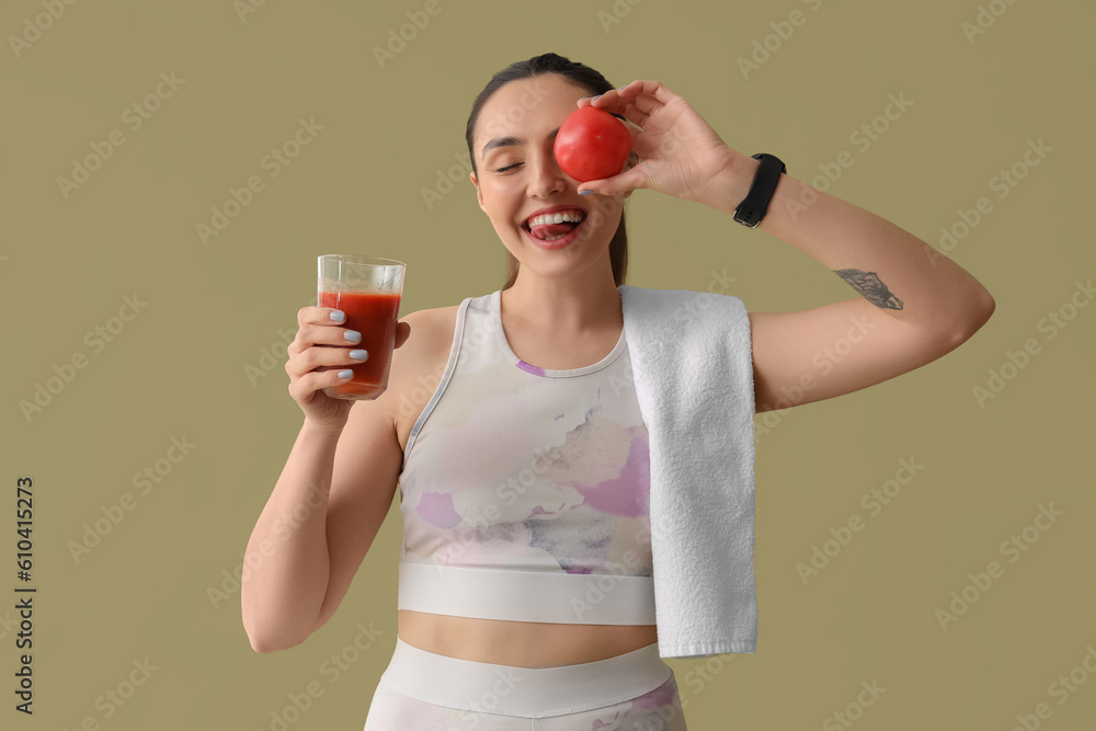 Sporty young woman with glass of vegetable juice and tomato on green background