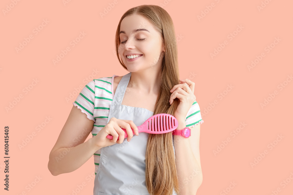 Female hairdresser brushing hair on pink background