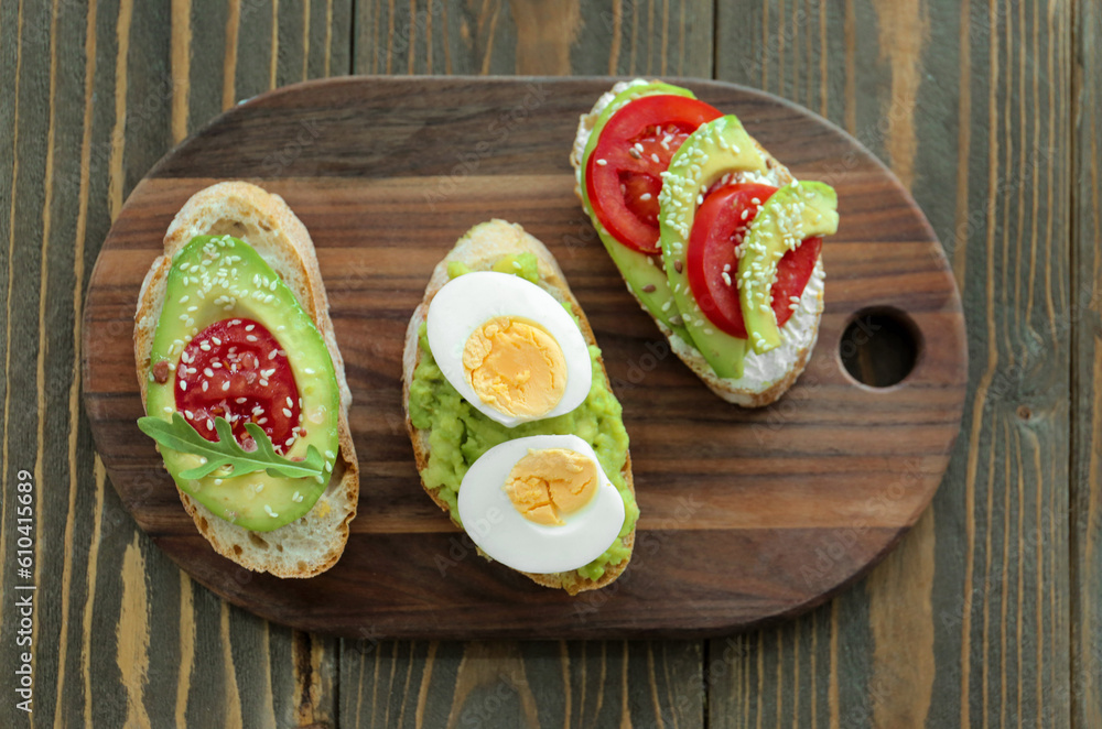 Board of tasty bruschettas with avocado on wooden background