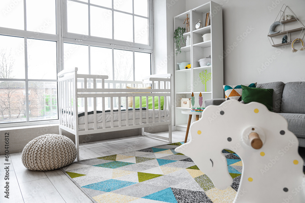 Stylish interior of childrens room with baby bed and shelving unit