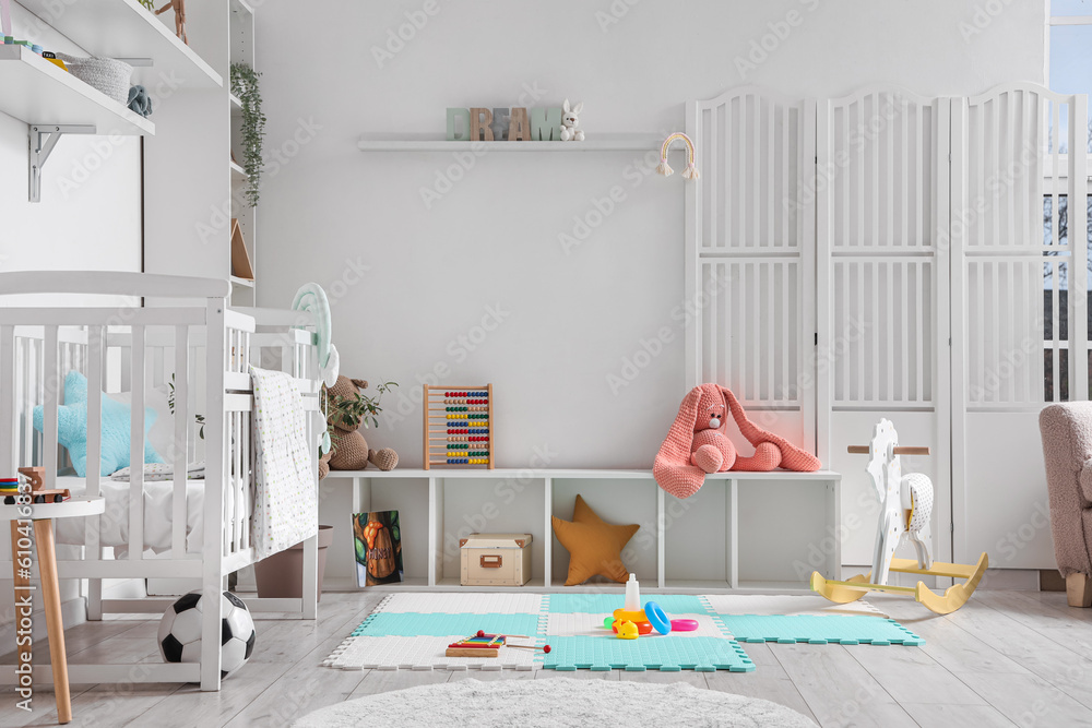 Stylish interior of childrens room with baby bed and toys