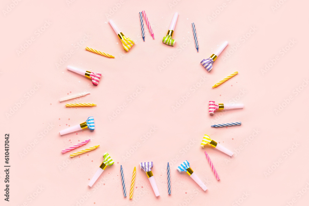 Frame made of whistles and candles for birthday party on pale pink background