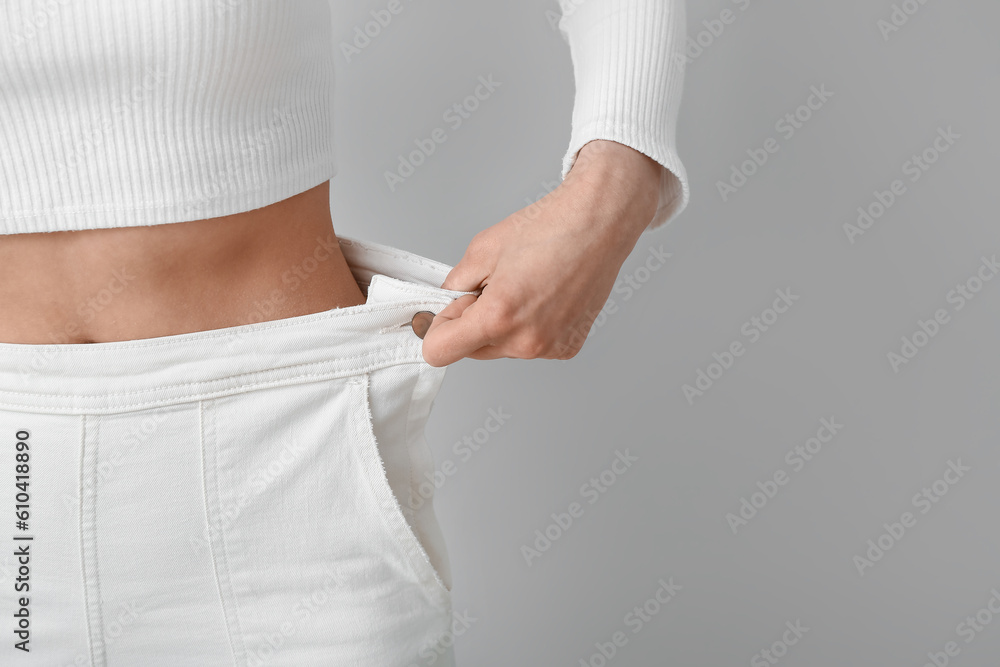 Young woman in loose pants on white background, closeup. Diet concept