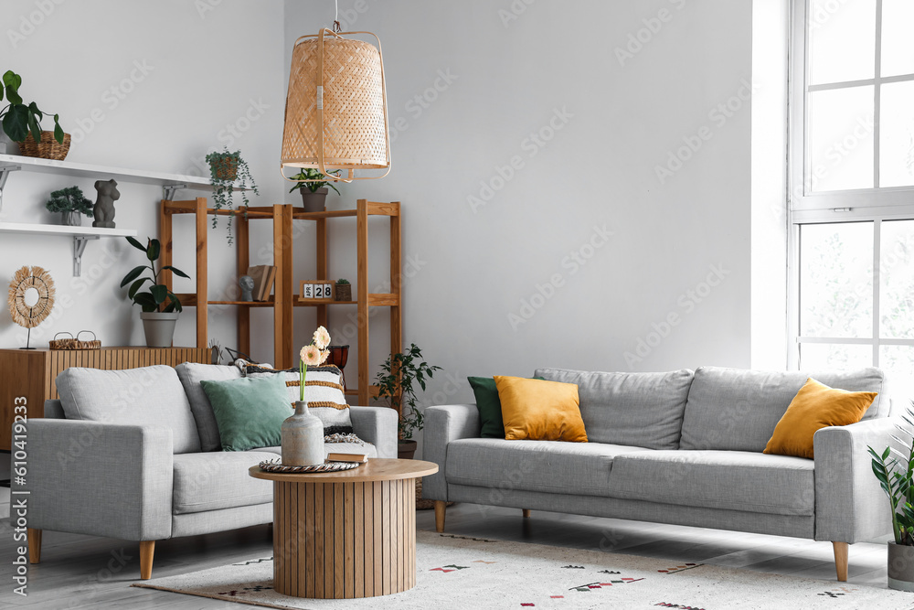 Interior of light living room with grey sofas, wooden coffee table and big window