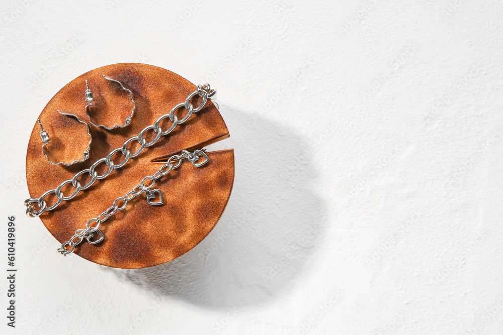 Decorative stand with silver earrings and bracelets on white textured background