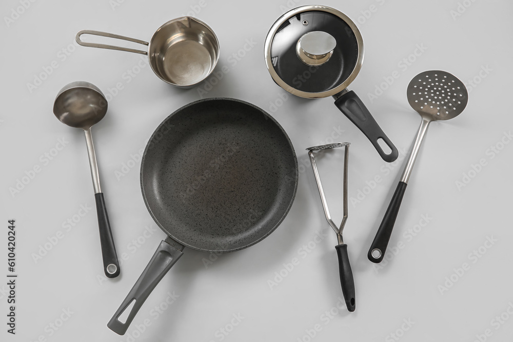 Cooking pot, frying pan and kitchen utensils on grey background