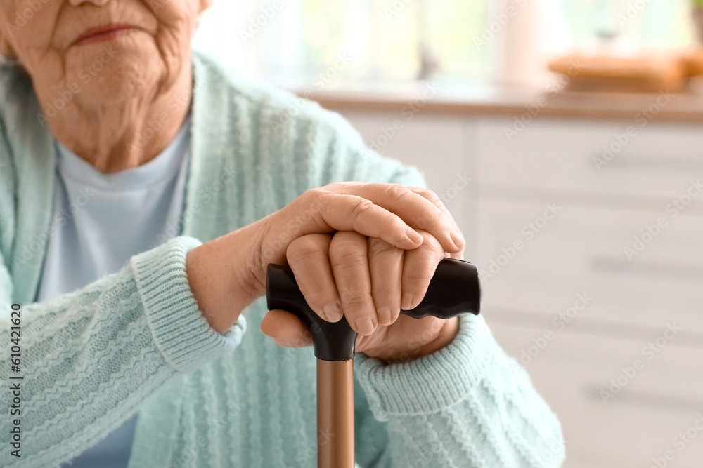 Senior woman with walking stick at home, closeup