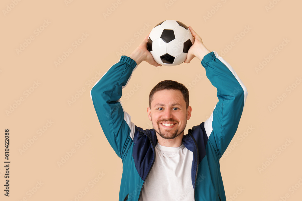 Happy man with soccer ball on beige background