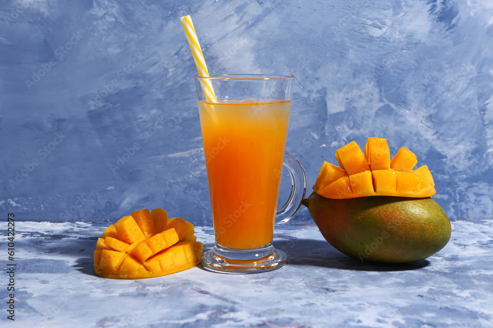 Glass of fresh mango smoothie on blue background