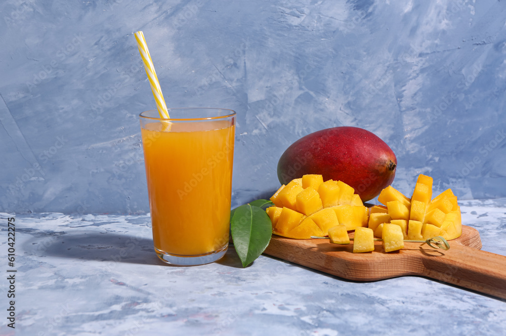 Glass of fresh mango smoothie on blue background