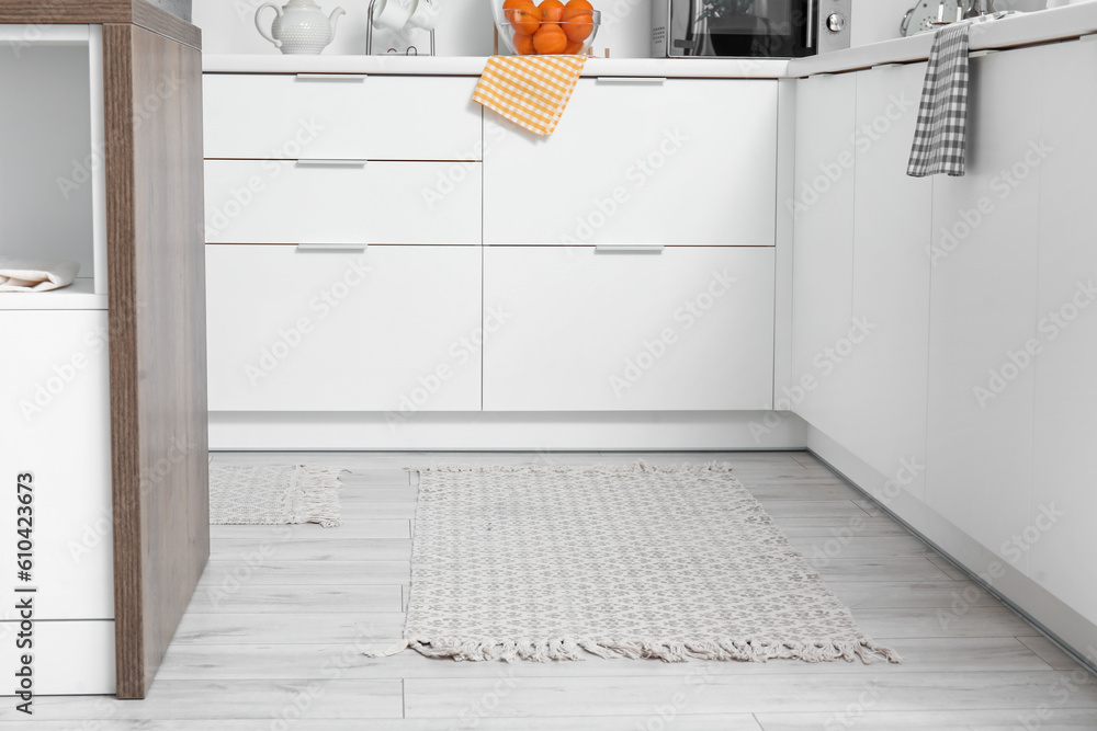 Stylish rug on floor in light kitchen