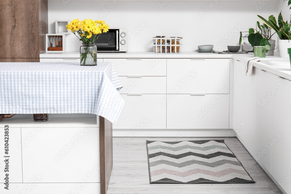 Stylish rug on floor in light kitchen