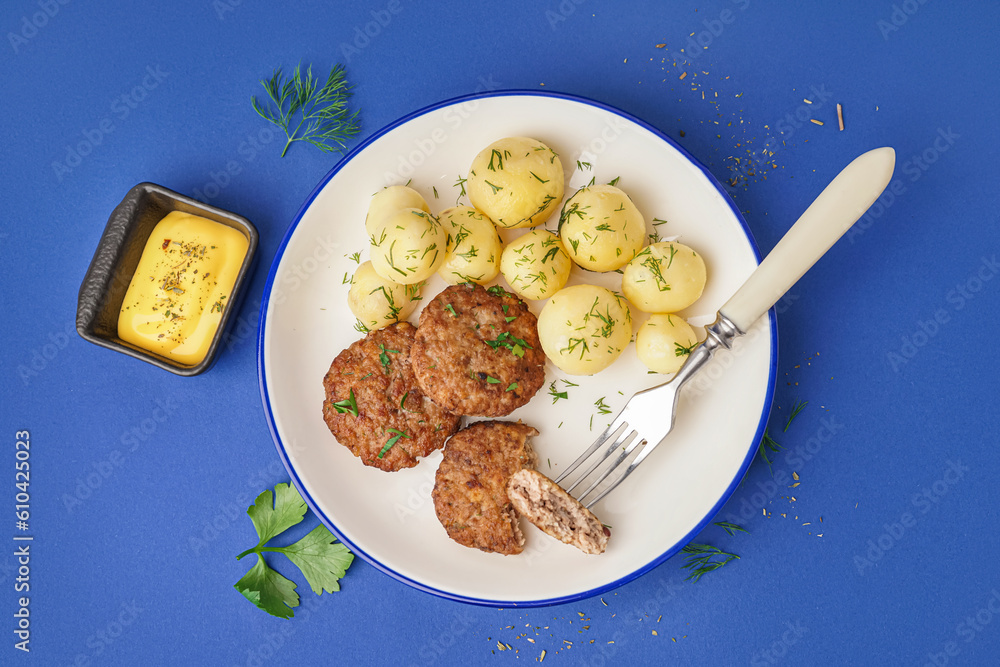 Plate with cutlets, boiled baby potatoes and dill on blue background