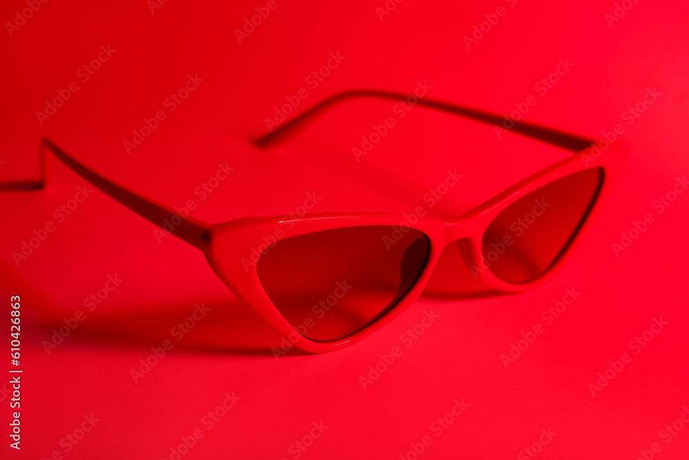 Stylish sunglasses on red background