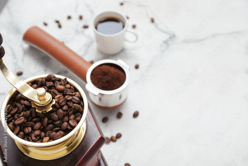 Coffee grinder with beans on white marble background