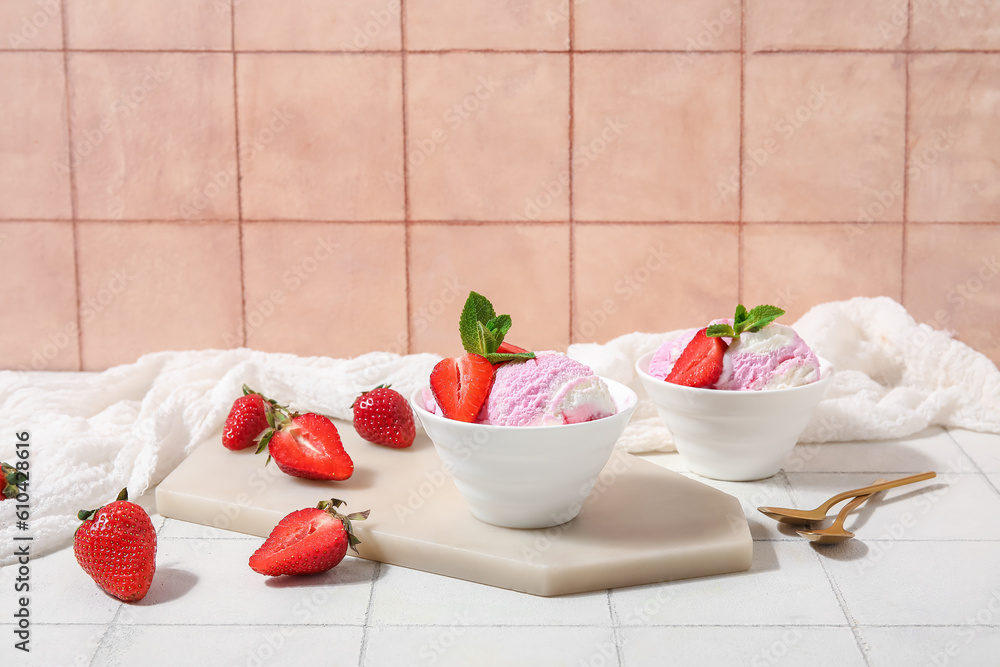 Bowls of strawberry ice cream and spoons on white tile table