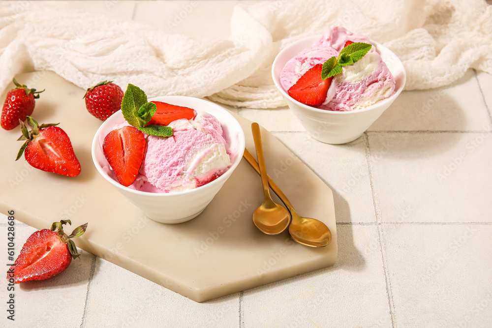 Bowls of strawberry ice cream and spoons on white tile table