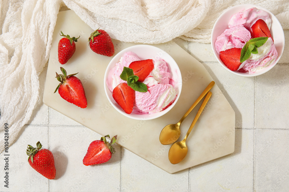 Bowls of strawberry ice cream and spoons on white tile table