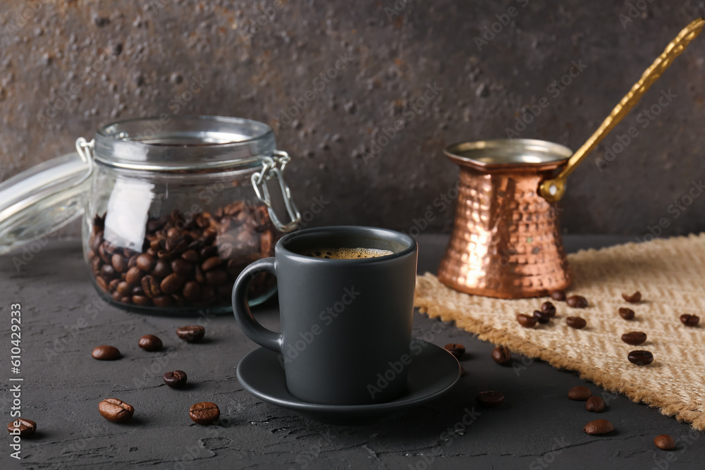 Cup of delicious espresso, coffee beans and jezve on table