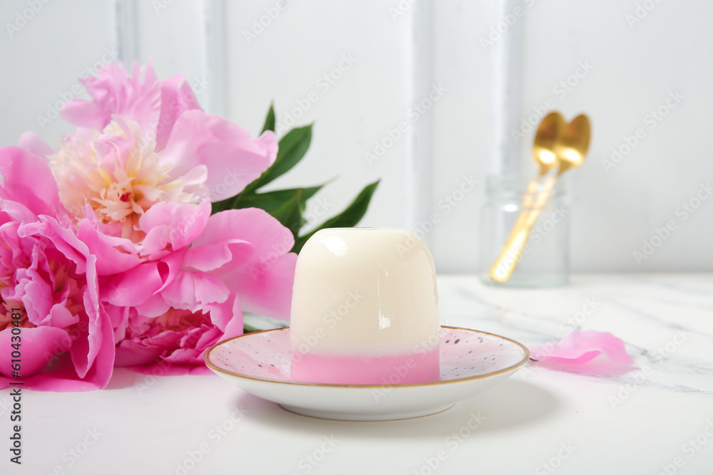 Plate of panna cotta with beautiful peony flowers on white table