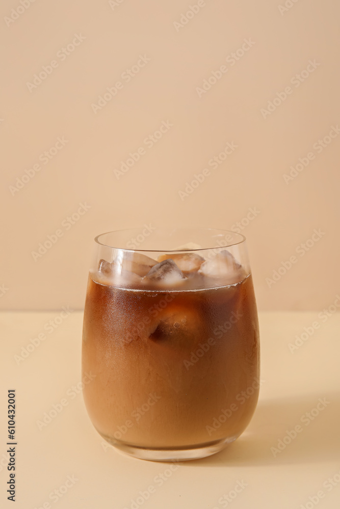 Glass with ice coffee on beige background