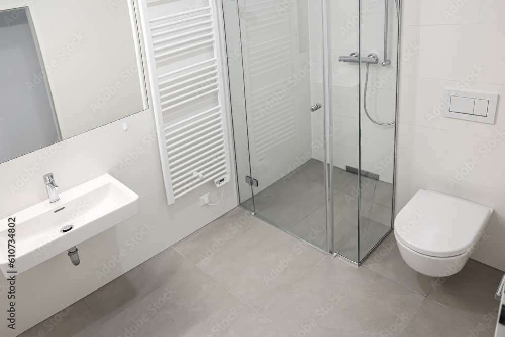 Interior of light bathroom with shower unit, toilet bowl and sink