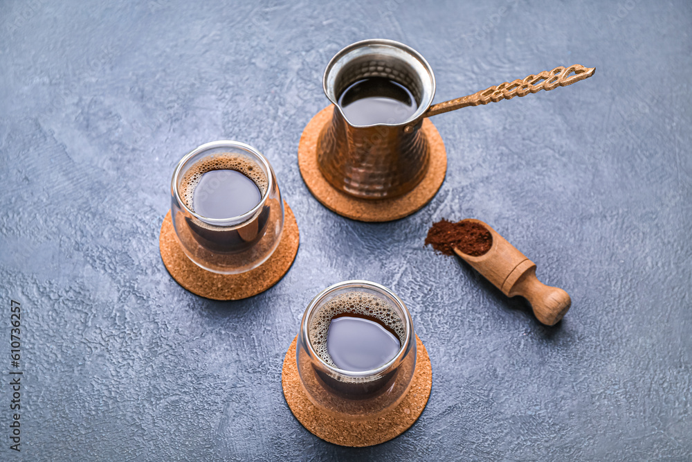 Drink coasters with glasses of coffee and jezve on blue table