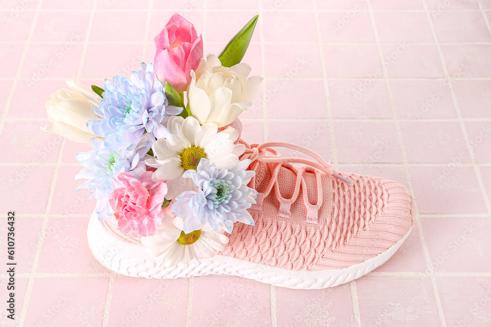 Sneaker with spring flowers on pink tile background