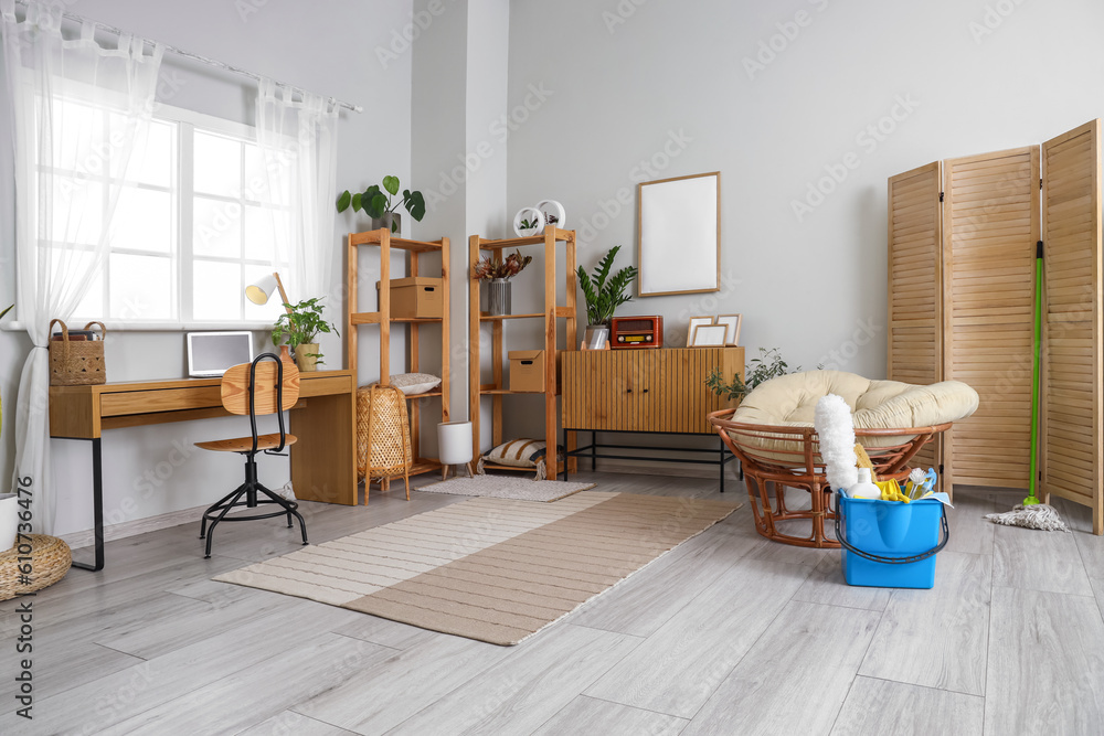 Interior of light room with modern workplace and cleaning supplies