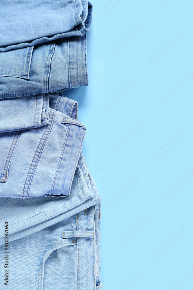 Stylish jeans on blue background, closeup