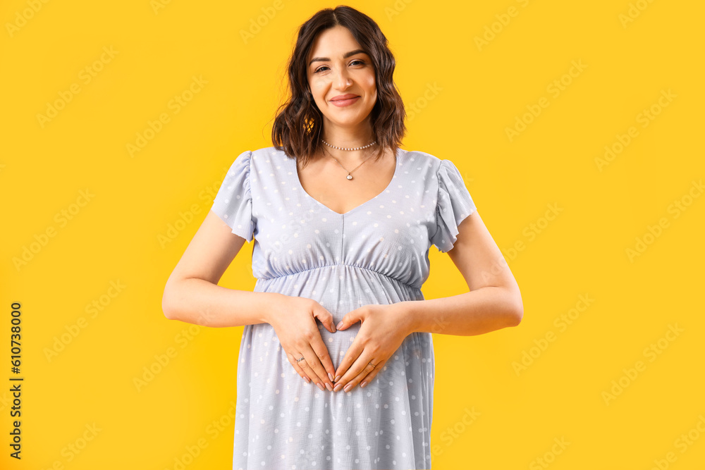 Young pregnant woman on yellow background