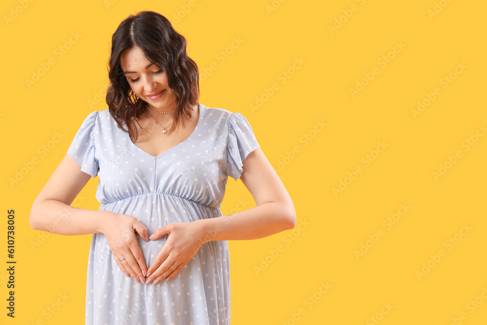 Young pregnant woman on yellow background