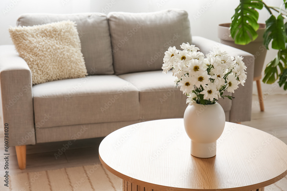 Vase with chrysanthemum flowers on wooden coffee table in living room