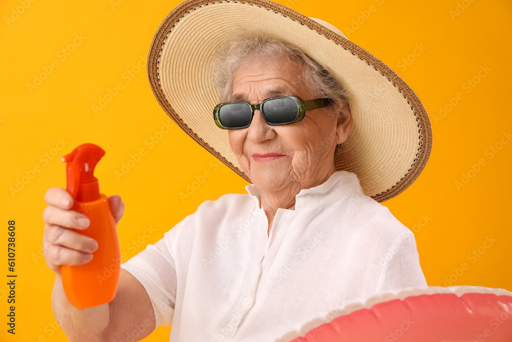 Senior woman with sunscreen cream on orange background, closeup