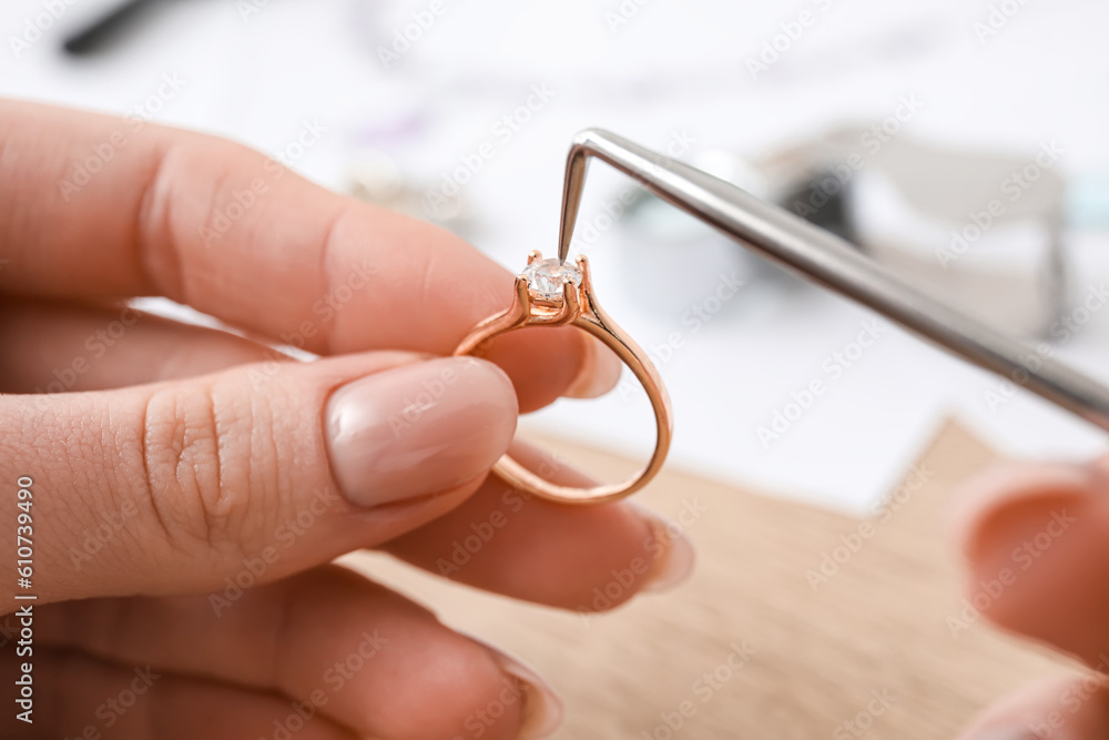 Female jeweler making ring on wooden table, closeup