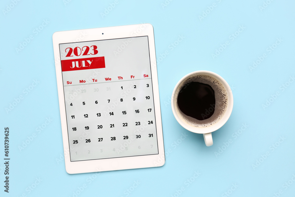 Modern tablet computer with calendar and cup of coffee on blue background