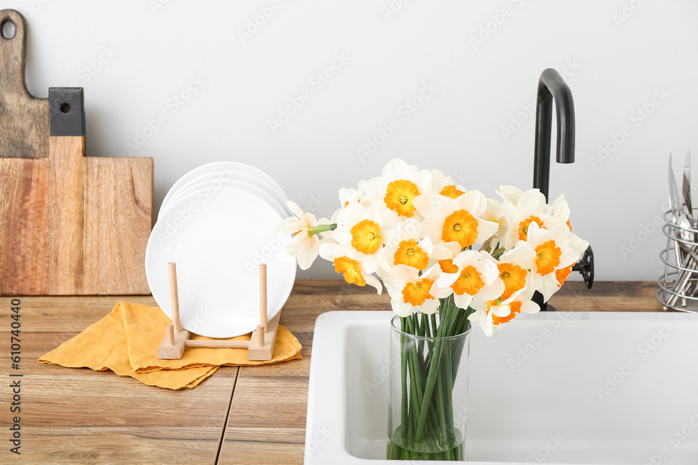 Vase with blooming narcissus flowers in sink, closeup