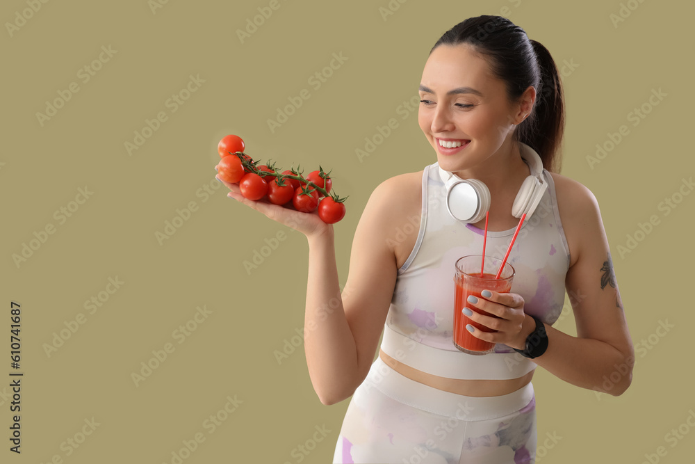 Sporty young woman with glass of vegetable juice and tomatoes on green background