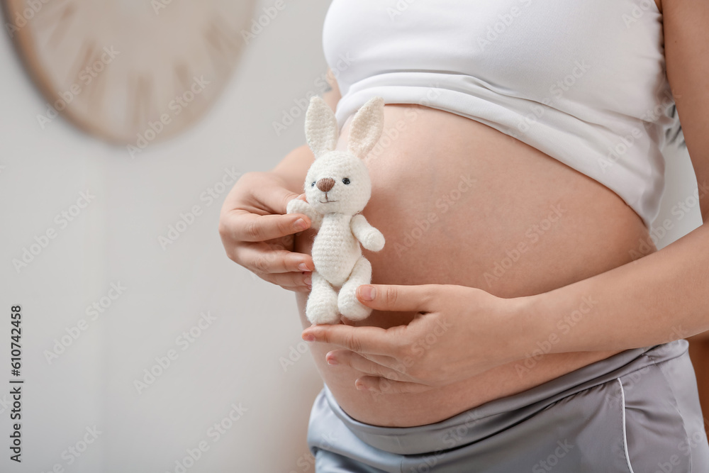 Young pregnant woman with toy in bedroom, closeup