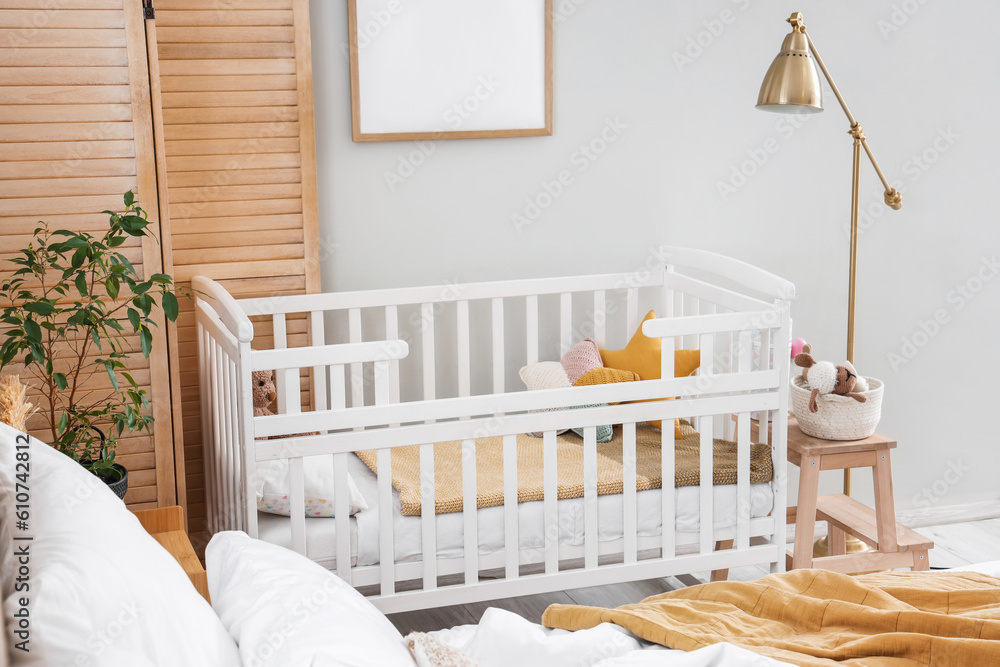 Baby crib in interior of light bedroom