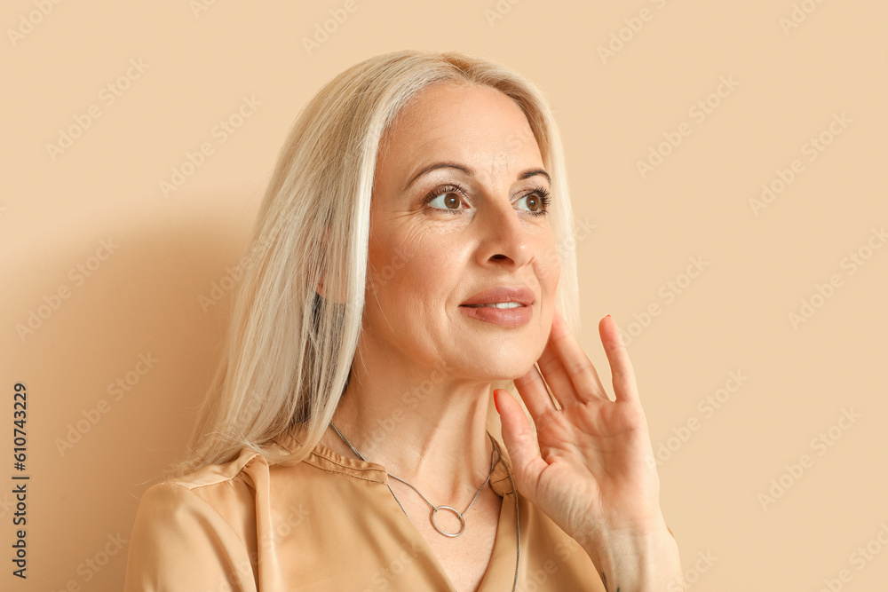 Mature blonde woman on beige background, closeup