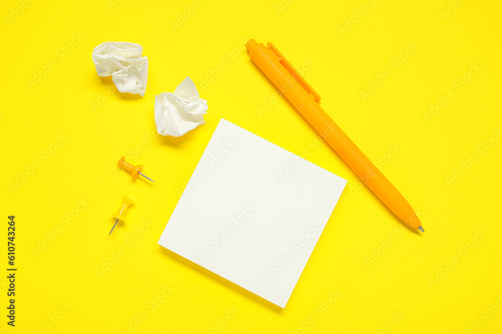 Pen with sticky notes and pins on yellow background