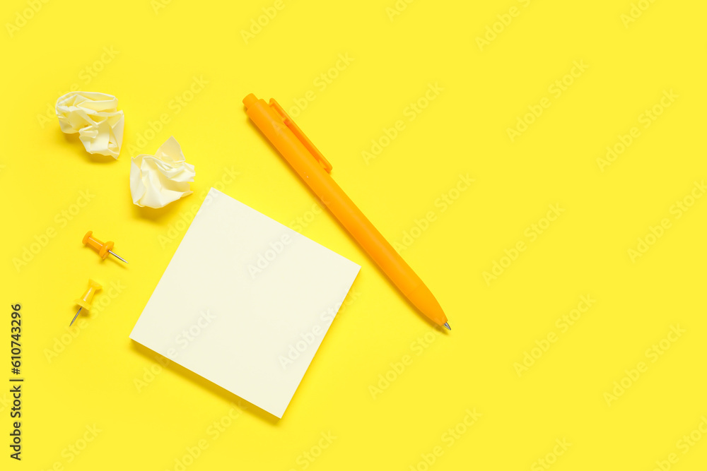 Pen with sticky notes and pins on yellow background