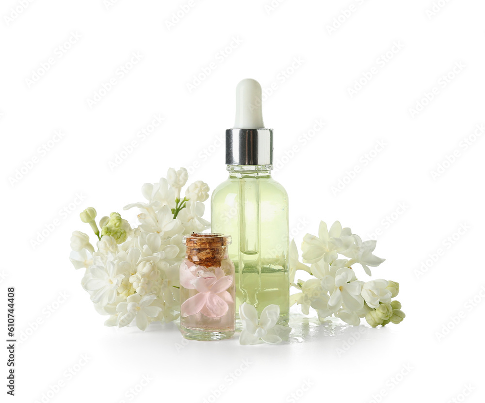 Bottles of cosmetic oil with beautiful lilac flowers on white background