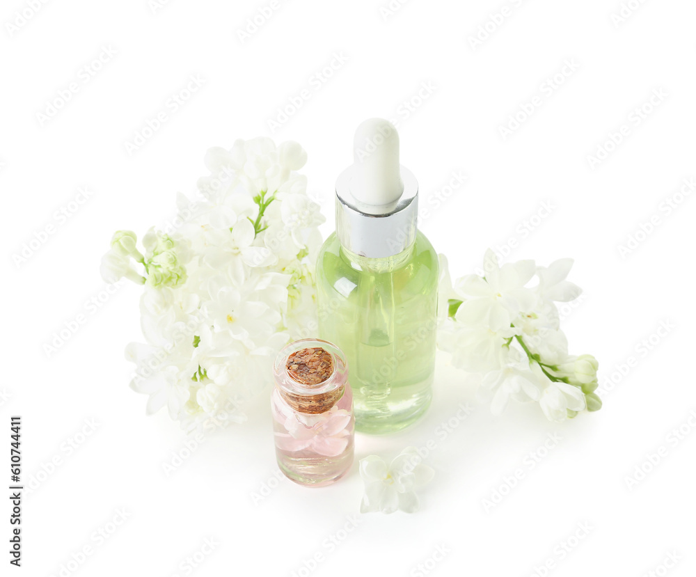 Bottles of cosmetic oil with beautiful lilac flowers on white background