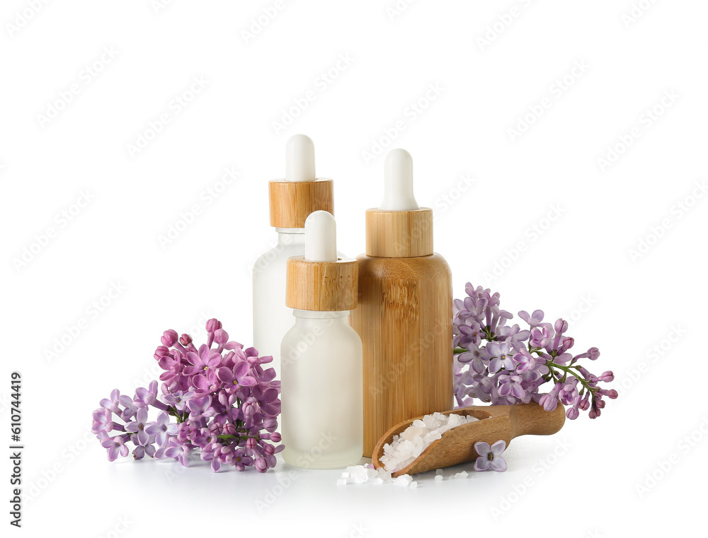 Bottles of cosmetic oil with beautiful lilac flowers and sea salt on white background