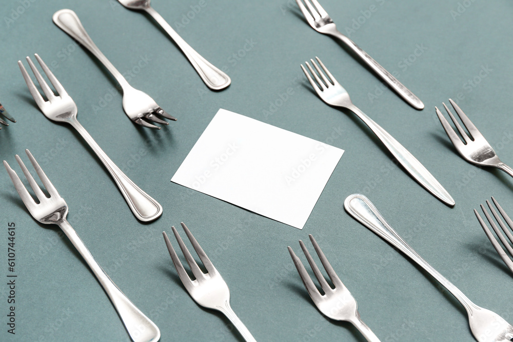 Composition with blank card and stainless steel forks on color background