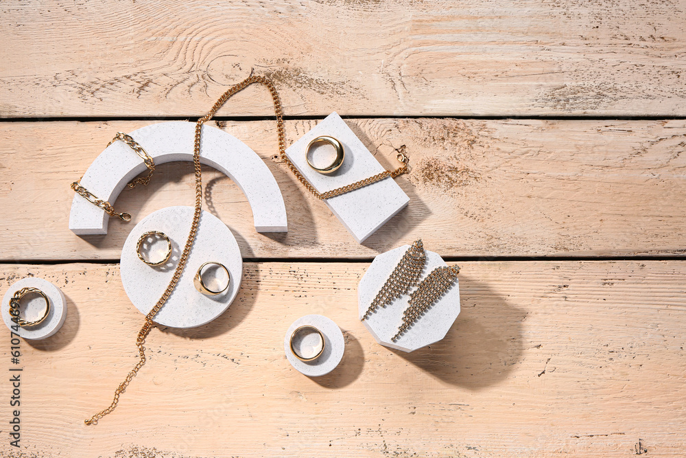 Decorative podiums with golden jewellery on wooden background